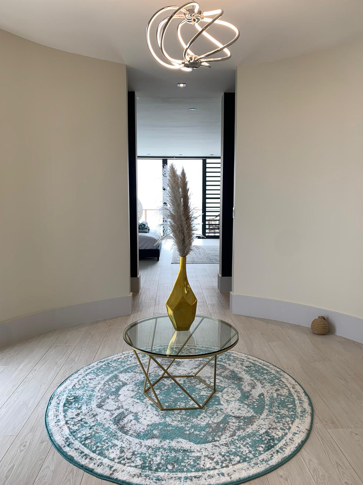 Luxury Bonaire villa master suite entrance featuring a modern sculptural light fixture, curved walls, and a view into the bedroom with private balcony access.
